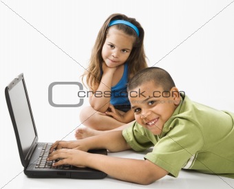 Hispanic boy on laptop with sister.