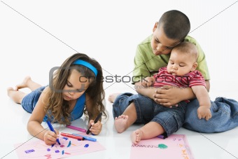 Hispanic girl coloring with brothers.