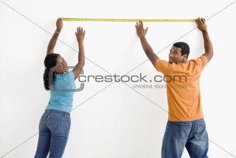 Couple measuring wall.