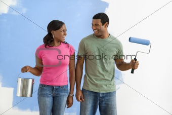 Smiling couple with paint supplies.