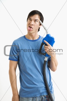 Man holding gas nozzle to head.