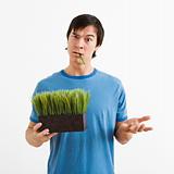 Man holding pot of grass.