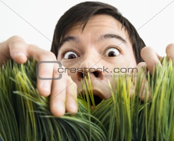 Surprised man behind grass.