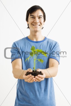 Smiling man holding plant.