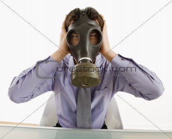 Man wearing gas mask with hands over ears.