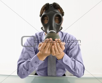 Man wearing gas mask with hands over mouth.