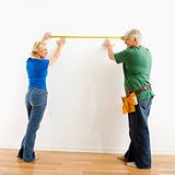 Man and woman measuring wall.