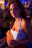 Young woman sitting at bar counter holding a drink 