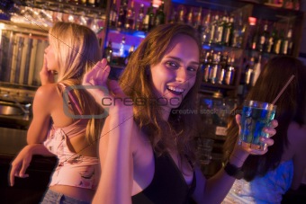 Young woman in nightclub smiling and waving at camera
