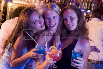 Three young women with drinks in a nightclub