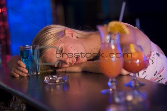 Drunk young woman resting head on bar counter
