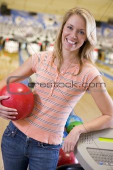 Young woman holding a bowling ball in a bowling alley