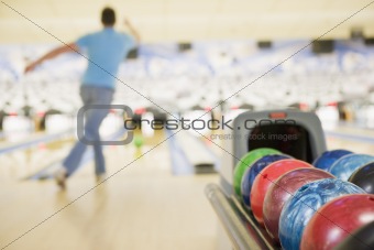 Bowling ball machine with man bowling in the background