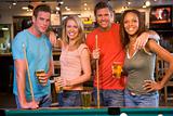 Two young couples standing beside a pool table in a bar