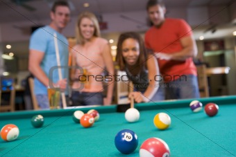 Young couples playing pool in a bar (focus on pool table)