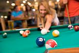Young woman playing pool in a bar (focus on pool table)