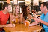 Group of young friends drinking and laughing in a bar
