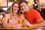 Happy young couple having beers at a bar