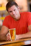 Young man relaxing at a bar with a beer 