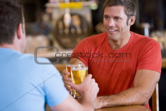 Two men toasting beer in a bar