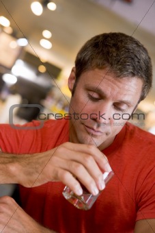 Young man at bar staring forlornly into drink