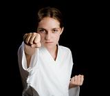 Pretty young girl in karate pose on black background