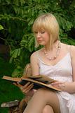 cute blond reads book in garden