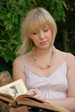 cute blond reads book in garden