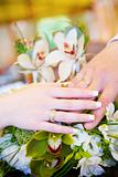two hands with wedding rings on the flower bouquet