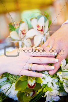 two hands with wedding rings on the flower bouquet