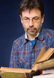 Mature man in glasses reads old book