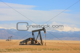 A Pumpjack pumping oil, snow capped mountain background