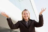 Businesswoman standing outdoors by building smiling with hands o