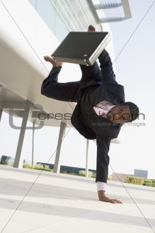 Businessman outdoors by building standing on one hand