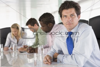 Four businesspeople in a boardroom writing