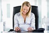 Businesswoman in office looking at personal organizer smiling