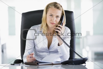 Businesswoman in office with personal organizer open on telephon