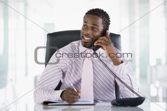 Businessman sitting in office with personal organizer open on te
