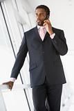 Businessman standing in corridor using cellular phone