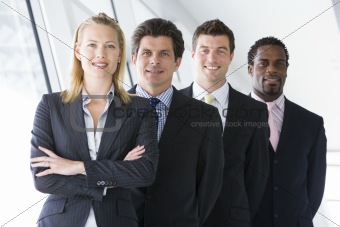 Four businesspeople standing in corridor smiling