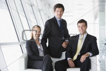 Three businesspeople sitting in office lobby smiling