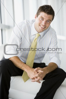 Businessman sitting in office lobby smiling