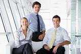 Three businesspeople sitting in office lobby smiling