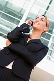 Businesswoman standing outdoors using cellular phone and smiling