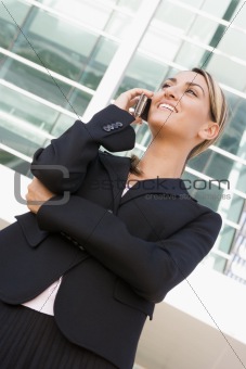 Businesswoman standing outdoors using cellular phone and smiling