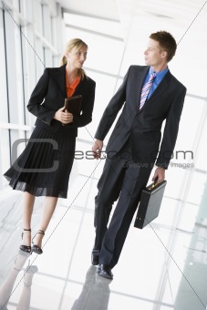 Two businesspeople walking in corridor talking