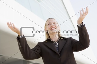 Businesswoman standing outdoors by building with hands out smili