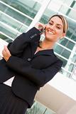 Businesswoman standing outdoors on cellular phone smiling