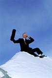Businessman outdoors on snowy mountain using cellular phone and 