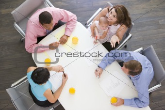 Four businesspeople in boardroom with one holding a baby smiling